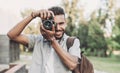 Young man photographer takes photographs with dslr camera in a city.