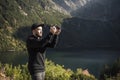 Young  man photographer taking photographs with digital camera in a mountains Royalty Free Stock Photo