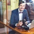 Young man photographer working at cafe, using dslr camera