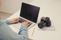Young man photographer working on a computer. Work desk with keyboard, camera, laptop and lenses Royalty Free Stock Photo