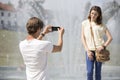 Young man photographing woman against fountain