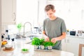 Young Man picking leaves of greenery during cooking. Home gardening on kitchen. Pots of herbs with basil, parsley, thyme Royalty Free Stock Photo