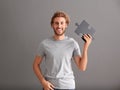 Young man with piece of jigsaw puzzle on grey background Royalty Free Stock Photo