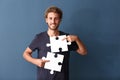 Young man with pieces of jigsaw puzzle on color background Royalty Free Stock Photo