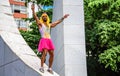 Young man in pink crown, yellow wig, leotard with pineapple and bright pink tutu skirt standing at the Memorial Getulio Vargas