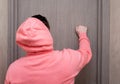 A young man in a pink hoodie in a karuchon is knocking on the door of a friend. Visit knock on the door Royalty Free Stock Photo