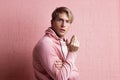 A young man in a pink hoodie on a pink background, portrait of a young stylish guy,