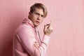 A young man in a pink hoodie on a pink background, portrait of a young stylish guy,