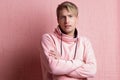 A young man in a pink hoodie on a pink background, portrait of a young stylish guy.