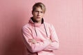 A young man in a pink hoodie on a pink background, portrait of a young stylish guy,