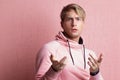 A young man in a pink hoodie on a pink background, portrait of a young stylish guy,