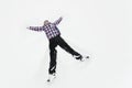 Young man in a plaid outerwear or jacket lies on the snow and makes the figure of an angel. Winter fun