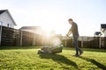 Young man in a plaid shirt and jeans mows lawn Royalty Free Stock Photo