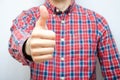 Young man in a plaid shirt with a smartphone on a white background. The guy shows his fingers up, like in front of  him Royalty Free Stock Photo