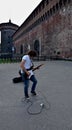 Young man plaing rock solo on guitar near Castello Sforzesco. Milan