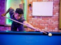 Young Asian man play billiards in the colorful club - Aiming white ball to shot Royalty Free Stock Photo