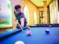 Young Asian man play billiards in the colorful club - Aiming white ball to shot Royalty Free Stock Photo