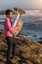 Young man play the trumpet on rocky sea coast during surf. Royalty Free Stock Photo