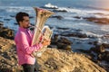 Young man play the trumpet on rocky sea coast Royalty Free Stock Photo