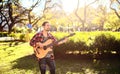 Young man playing acoustic bass guitar in the park