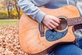 Young man playing acoustic guitar close up outdoors in autumn park Royalty Free Stock Photo