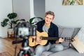 Young man playing acoustic guitar and recording music video for his social networks. Amatuer musician create content at Royalty Free Stock Photo