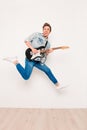 Young man playing on electric guitar, showing tongue and jumping Royalty Free Stock Photo