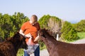 Young man playing and feed wild donkey, Cyprus, Karpaz National Park Wild Donkey Protection Area. Royalty Free Stock Photo