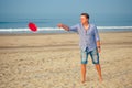 Young man playing flying disk with friends on the beach Royalty Free Stock Photo
