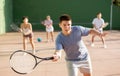 Young man playing frontenis at open-air fronton court in summer