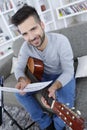 Young man playing guitar and sitting on couch Royalty Free Stock Photo