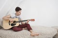 Young man playing guitar while sitting on fur sofa Royalty Free Stock Photo