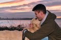 Young man playing and hugging his golden retriever dog at a sunset Royalty Free Stock Photo