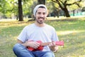 Young man playing the ukelele in a park. Royalty Free Stock Photo
