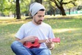 Young man playing the ukelele in a park. Royalty Free Stock Photo