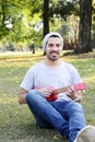 Young man playing the ukelele in a park. Royalty Free Stock Photo