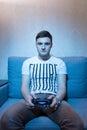 Young man playing a video game while sitting on the sofa at home