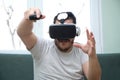 Young man playing video games with virtual reality headset and a joystick sitting on sofa Royalty Free Stock Photo