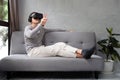 Young man playing video games in virtual reality headset while sitting on sofa at home Royalty Free Stock Photo