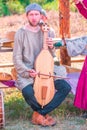 A young man plays an ancient stringed instrument. Military history festival `Military case