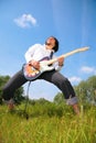 Young man plays on guitar on grass Royalty Free Stock Photo