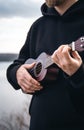 A young man plays the ukulele guitar in nature on a blurred background. Royalty Free Stock Photo