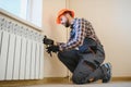 young man plumber checking radiator while installing heating system in apartment