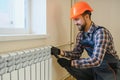 young man plumber checking radiator while installing heating system in apartment