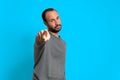 Young man pointing finger at camera in studio portrait on blue background. positive attitude of success and winner. copy space Royalty Free Stock Photo