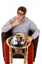 Young man pondering life with world globe in chair Royalty Free Stock Photo