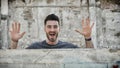 Young man popping out from behind a small wall