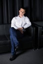 Young man posing in the armchair on the dark background Royalty Free Stock Photo