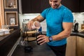 Young man pouring a tasty berry shake into his drinking cup in the kitchen, delicious healthy treats Royalty Free Stock Photo