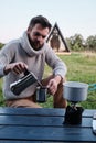 Young man pours coffee from a geyser coffee maker